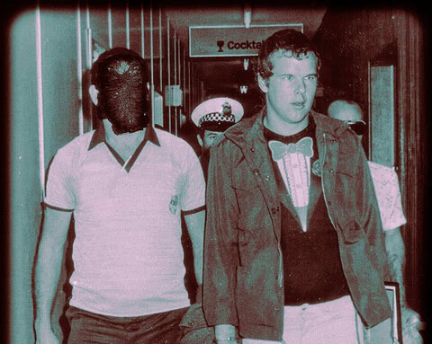 Vintage tinted photo of a young man walking with police officers indoors.