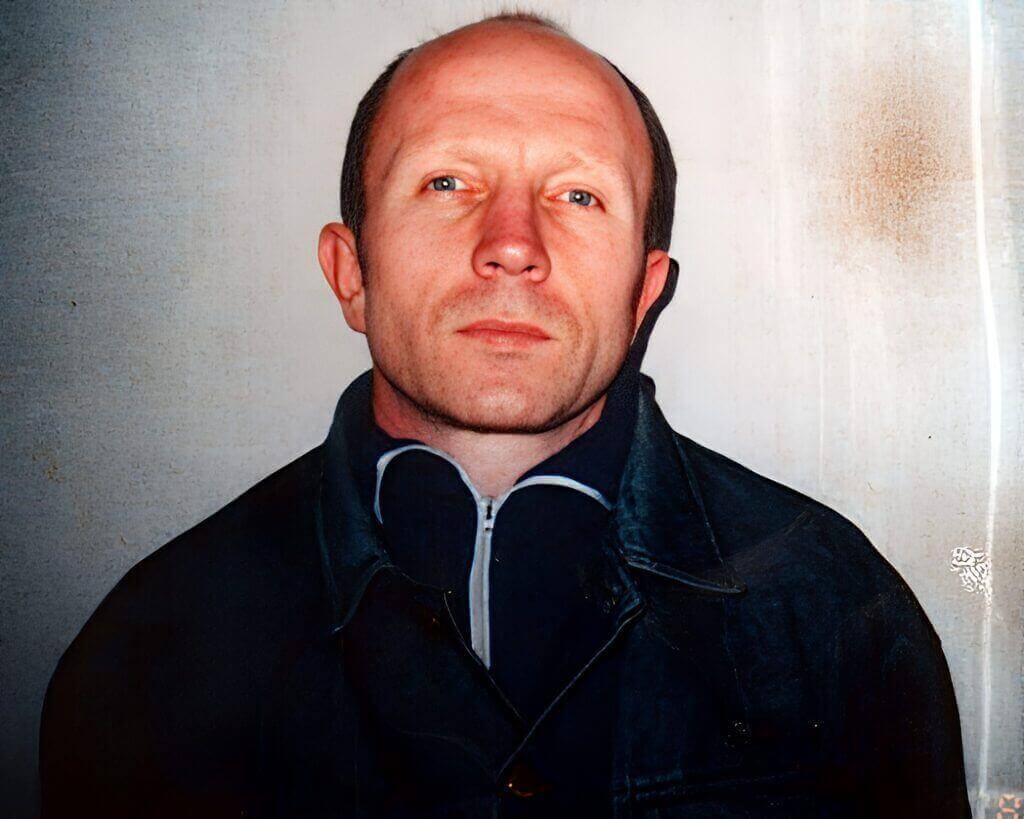 Portrait of a man with a serious expression, wearing a dark jacket.