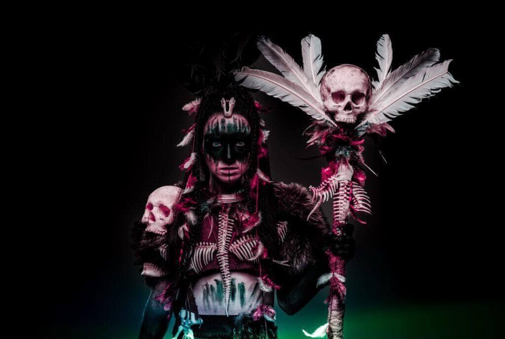 Dark ritual performer with skull staff and tribal face paint for The Dark Side of Humanity.