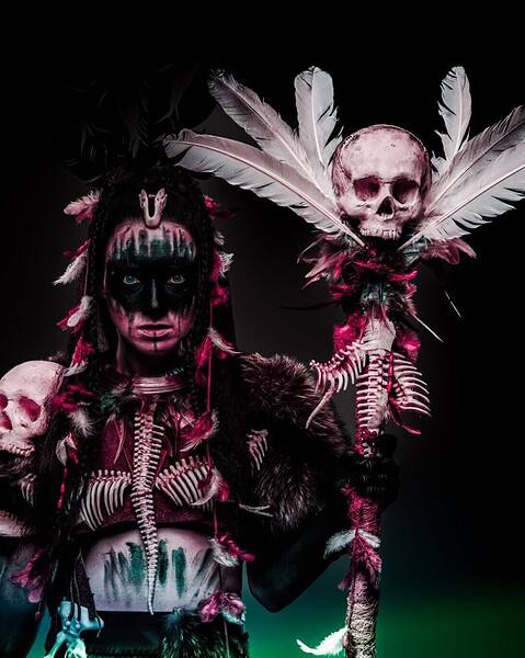 Dark ritual performer with skull staff and tribal face paint for The Dark Side of Humanity.