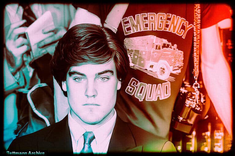 A young man pictured in front of an officer wearing an Emergency Squad jacket.