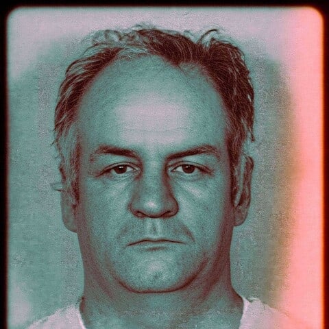 Close-up mugshot photograph of a middle-aged man with receding hair facing the camera.