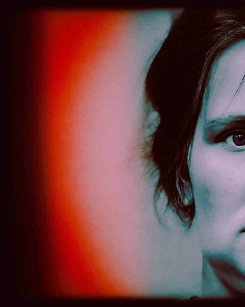 Stylised tinted portrait of a woman with short dark hair facing the camera.