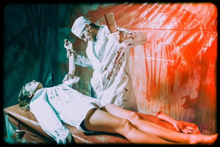 A staged, stylised scene showing a figure in a white medical uniform standing over a person lying on a table.
