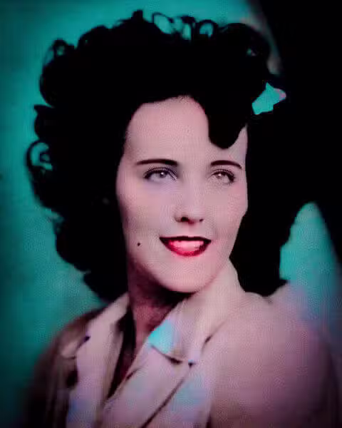 Colourised portrait photograph of Elizabeth Short, a young woman with dark curled hair and red lipstick.