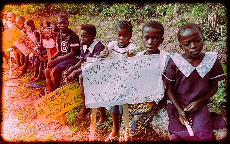 Children protest for equality and justice, holding signs about witches, wizards, and societal issues in a rural environment.