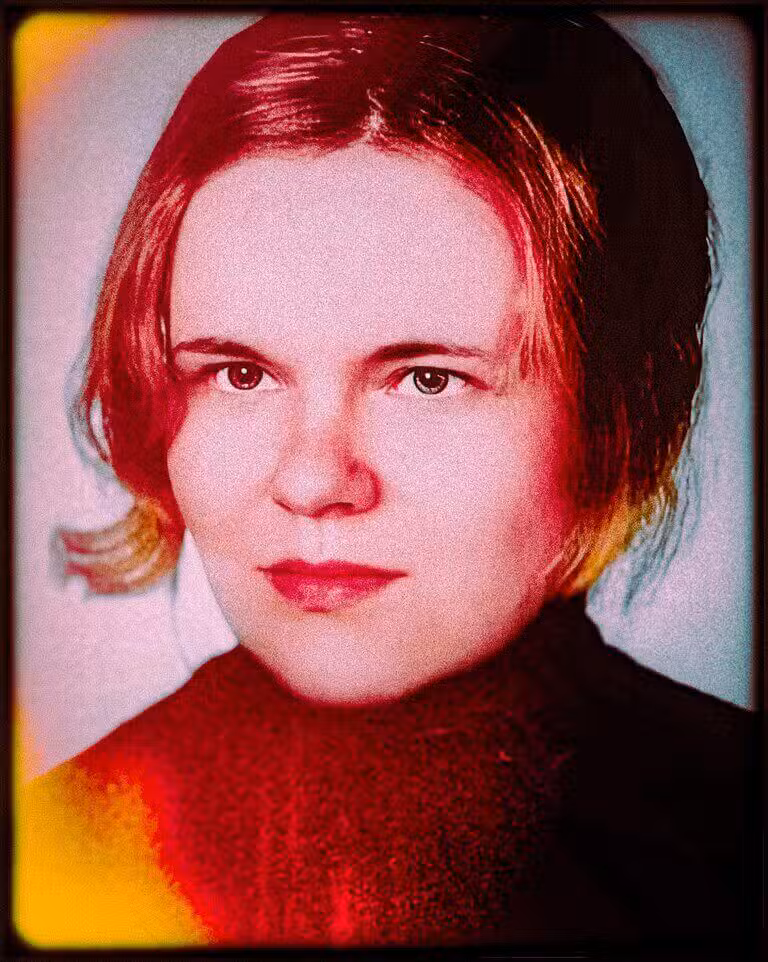 A grainy colourised close-up photograph of a young woman with short hair wearing a dark sweater.