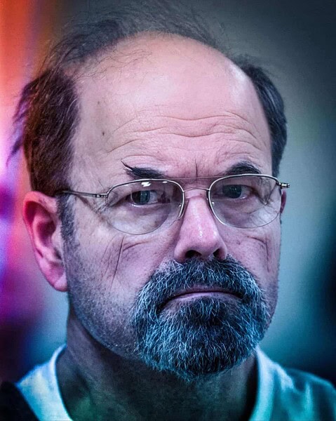 Close-up of a man with glasses showing the dark side of human nature and evil.