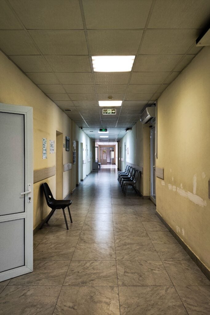 Empty hospital corridor with chairs and open doors. necrosadism