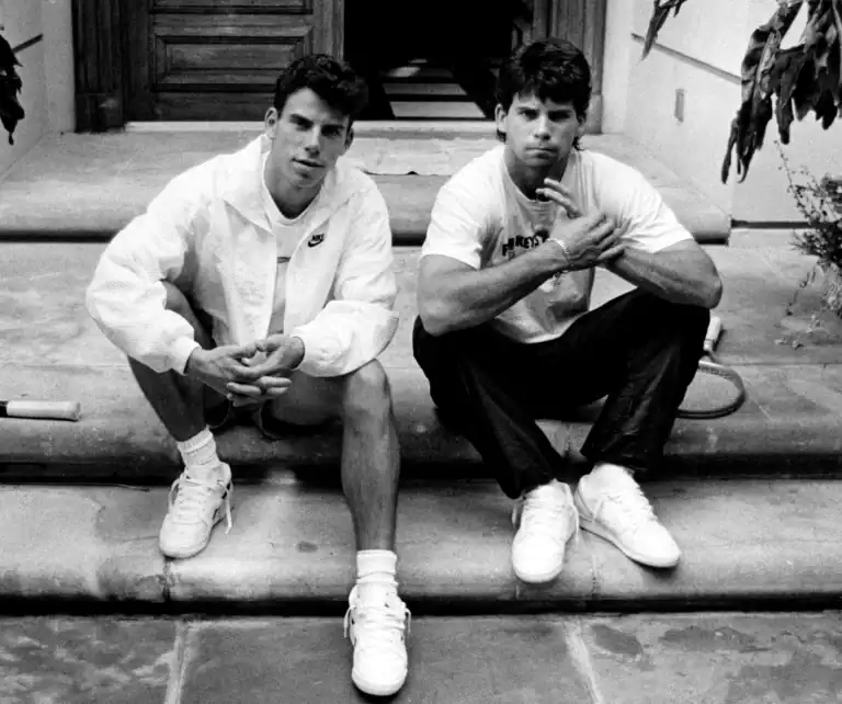 Black and white photo of two young brothers sitting side by side on a step outdoors.