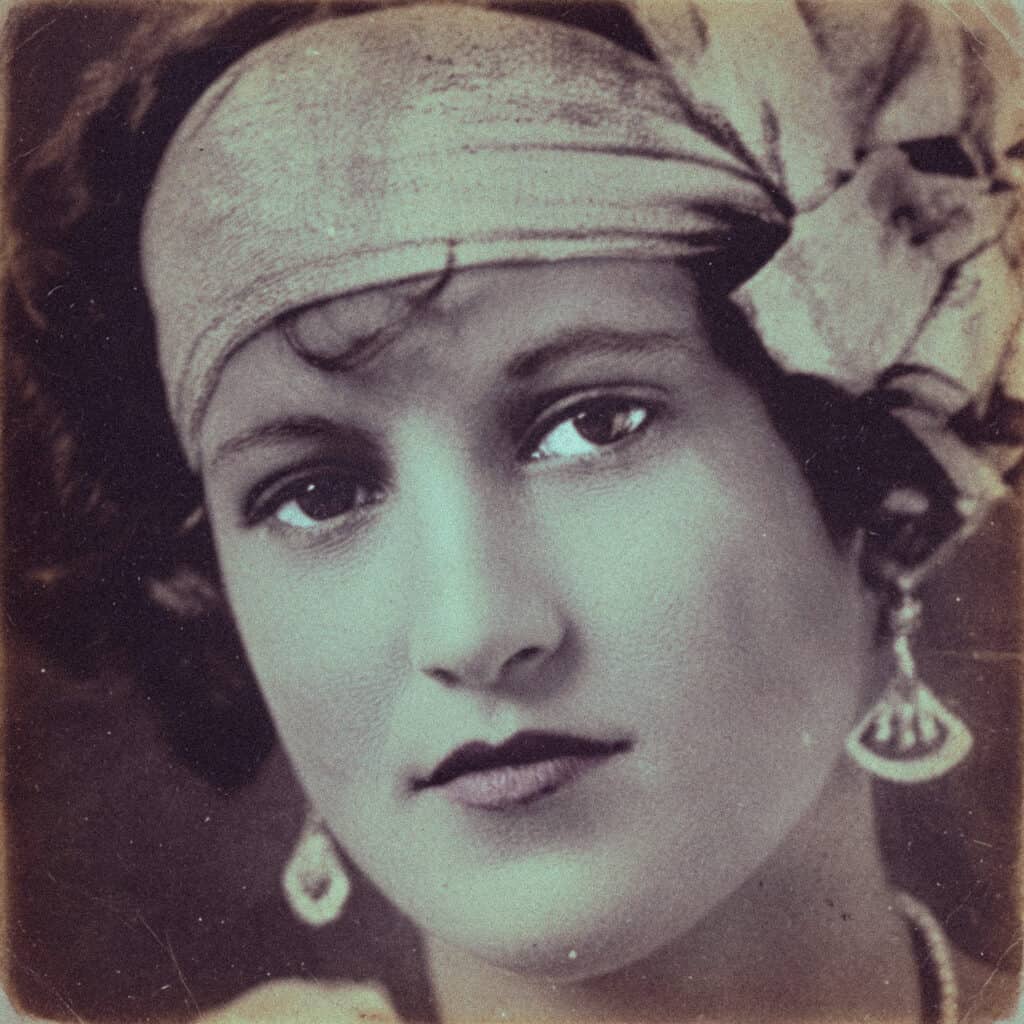 A close-up sepia-toned vintage portrait of a young woman wearing a pale headscarf.