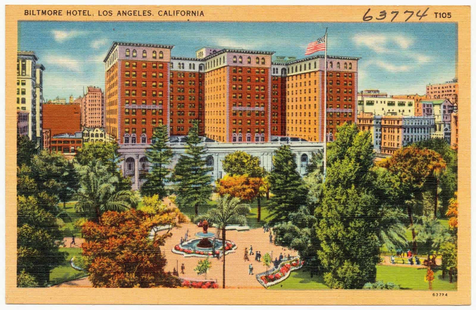 Colour postcard of the Biltmore Hotel, a large brick building with towers, seen across a park with palm trees.