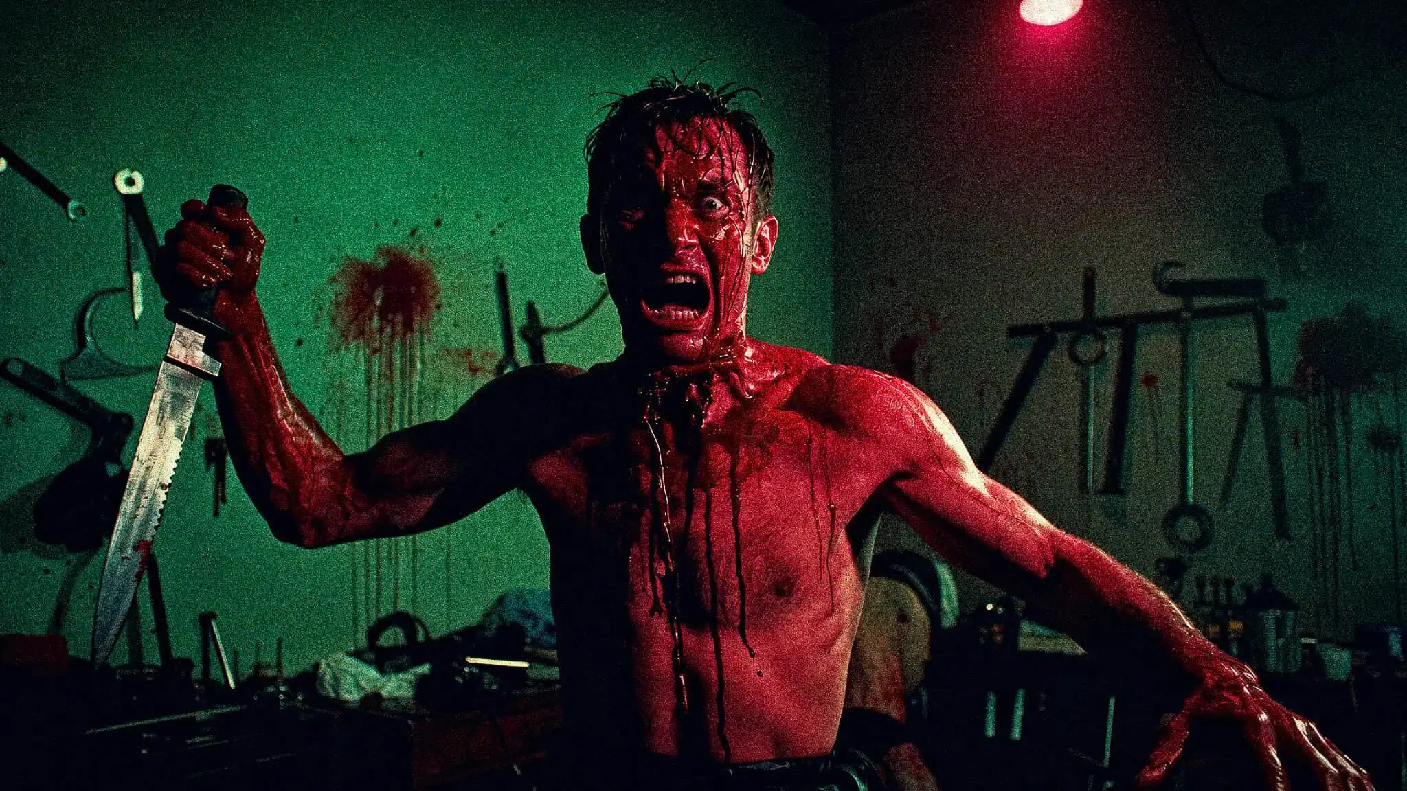 Terrified man covered in blood in a dark, eerie room with medical tools.