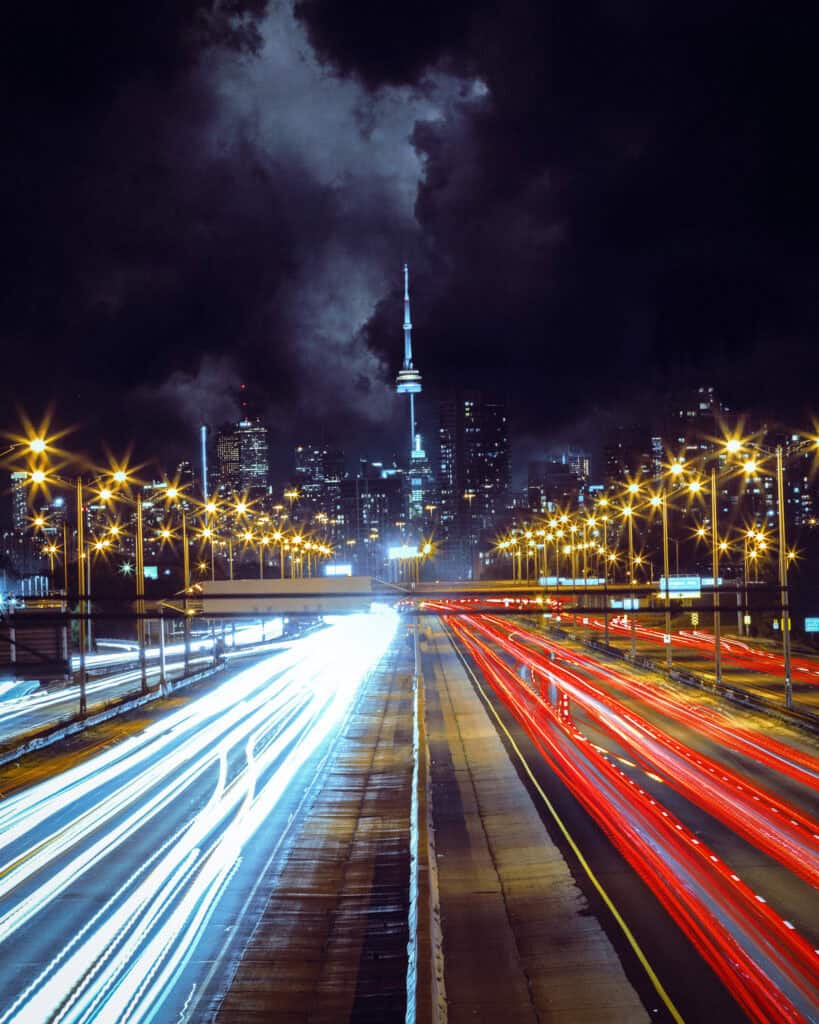 Night cityscape with illuminated roads and city skyline with CN Tower.