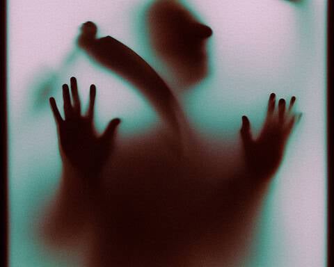 Faint silhouette of a person pressing against a foggy glass surface.