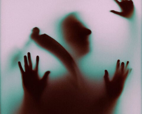 Faint silhouette of a person pressing against a foggy glass surface.
