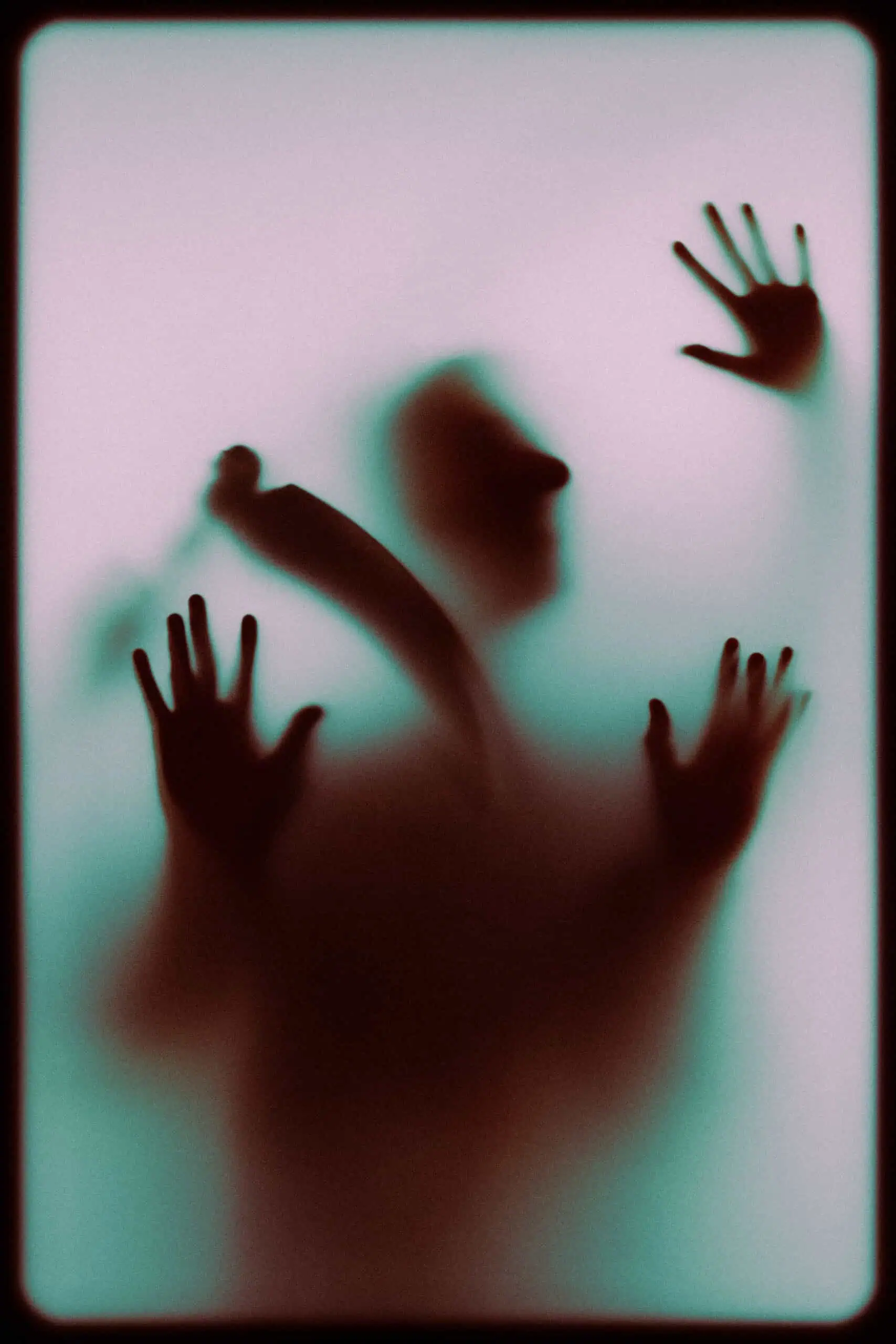 Faint silhouette of a person pressing against a foggy glass surface.