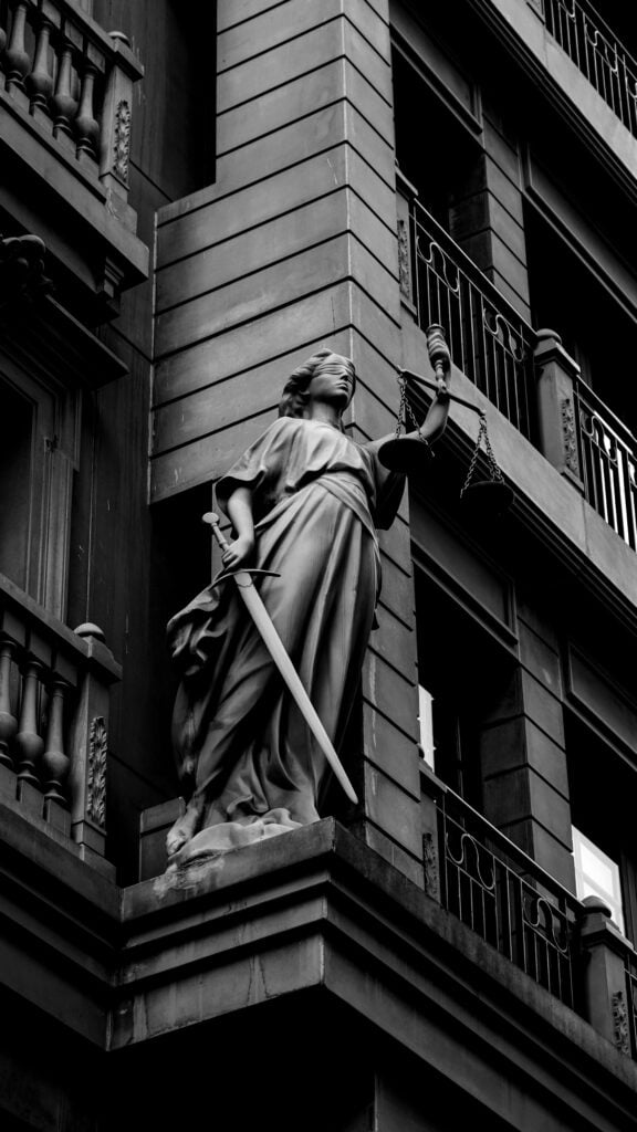 Black and white photo of a statue on a city building facade.