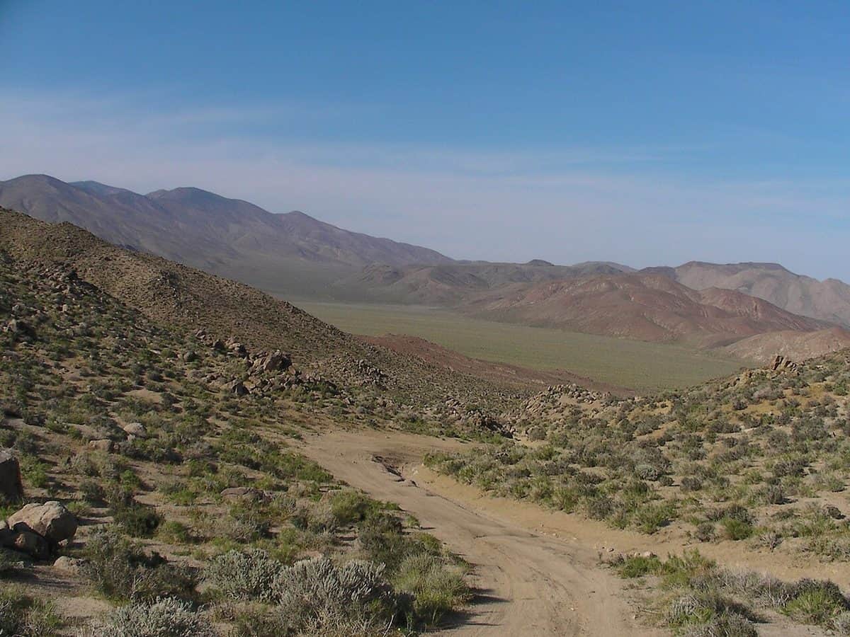 A rocky, dry desert wash between steep brown slopes under a pale sky