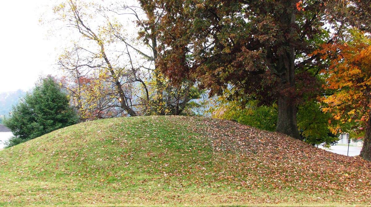 A grassy prehistoric burial mound under autumn trees on the University of Tennessee agricultural campus