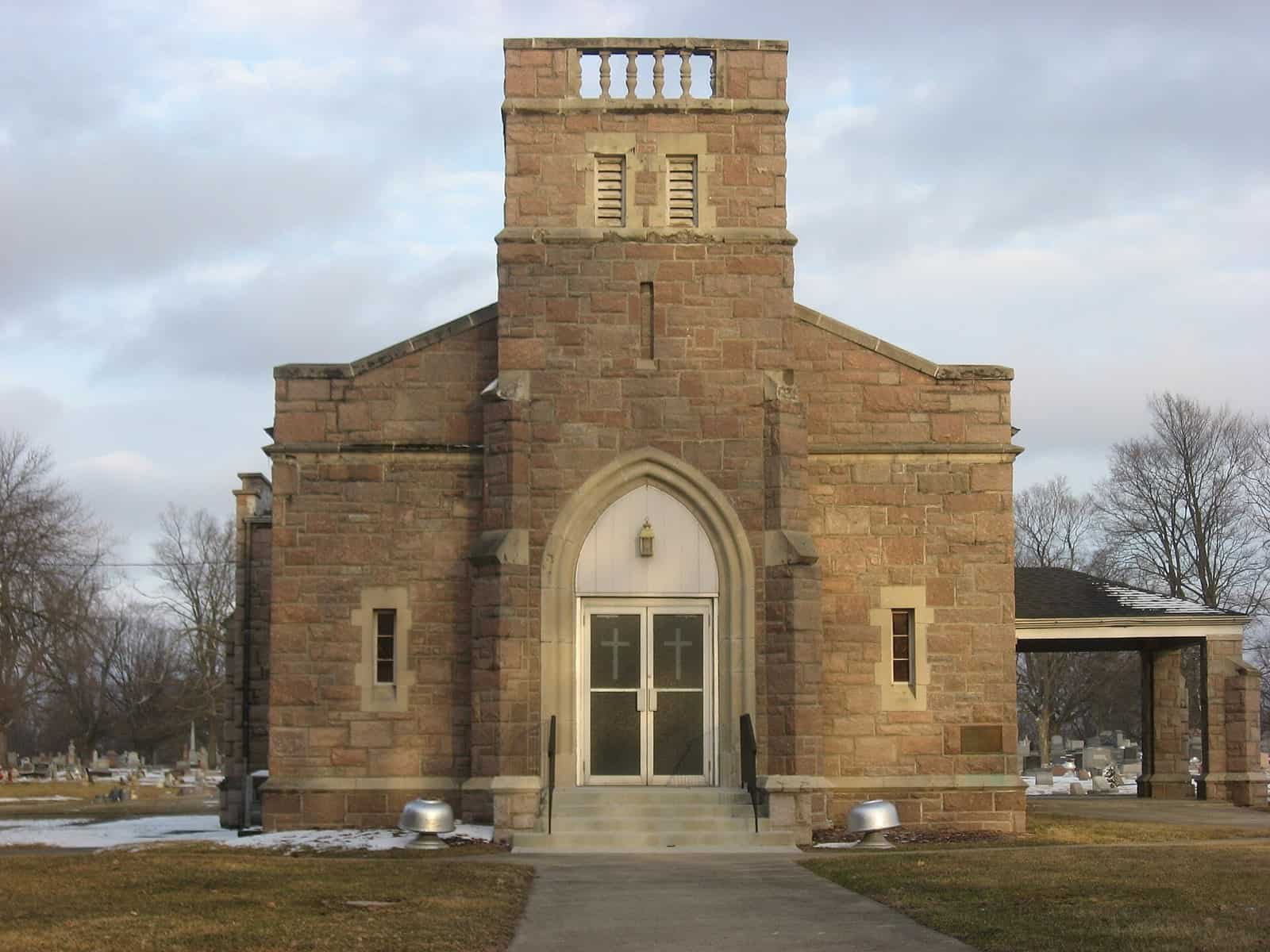 A small stone chapel at the entrance to Oak Hill Cemetery in Lebanon, Indiana, with bare trees around it