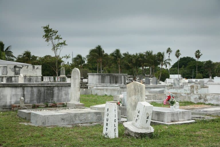 Rows of white above-ground tombs in Key West Cemetery under a blue sky.