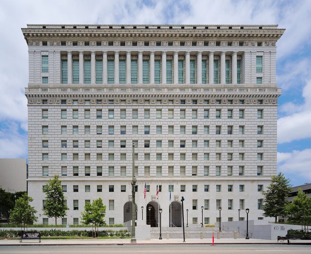 The restored Los Angeles Hall of Justice, a large Beaux-Arts granite building with tall columns at its upper floors, seen from street level in downtown Los Angeles.