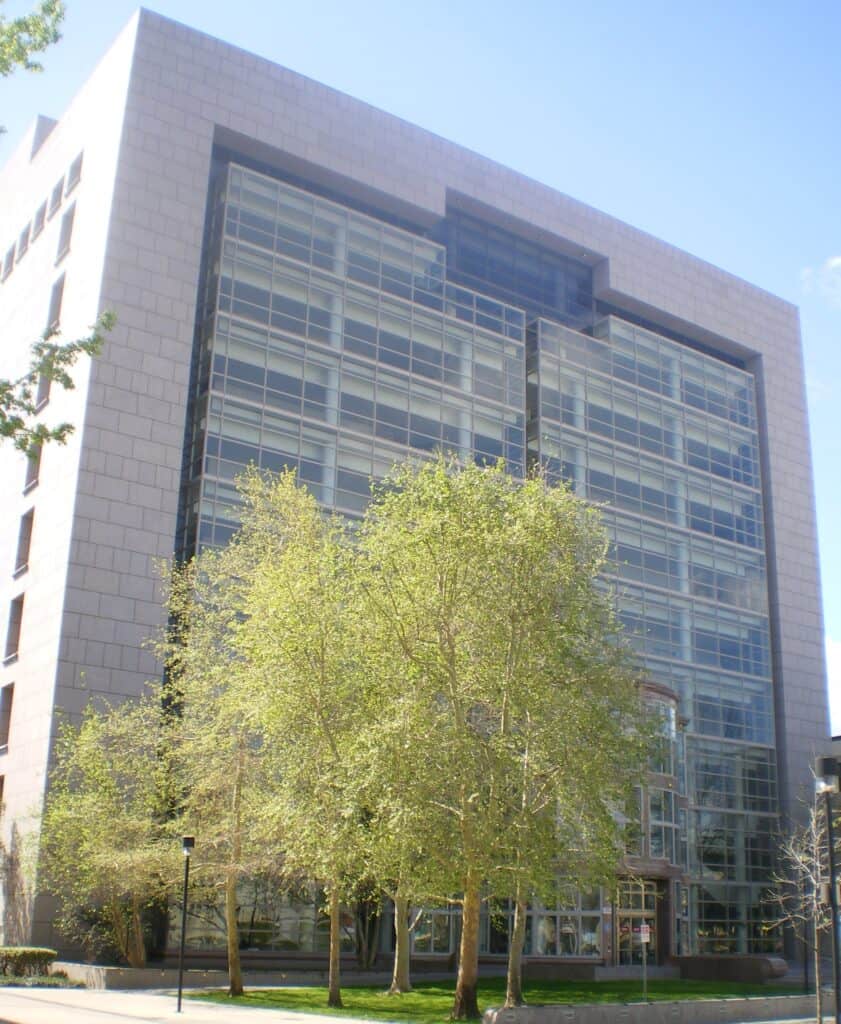 A tall modern courthouse with a stone frame and a glass curtain wall, with young trees on a lawn in front, in Van Nuys.