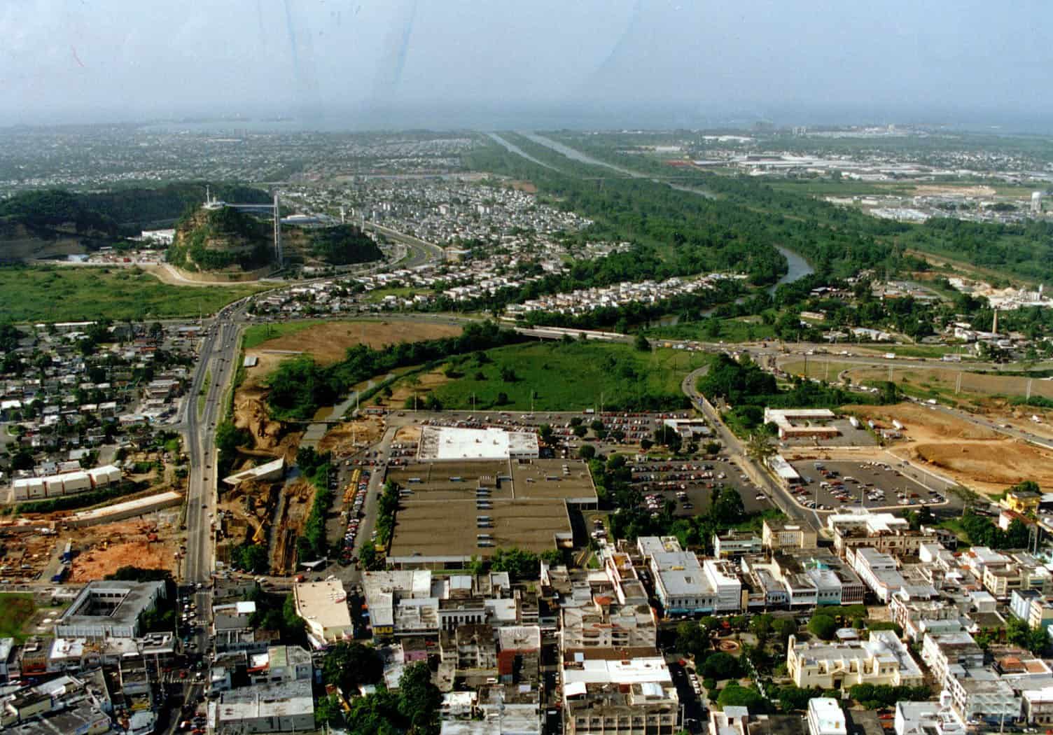 Aerial view of the city of Bayamón, Puerto Rico, with low buildings, highways and a river running north toward the coast
