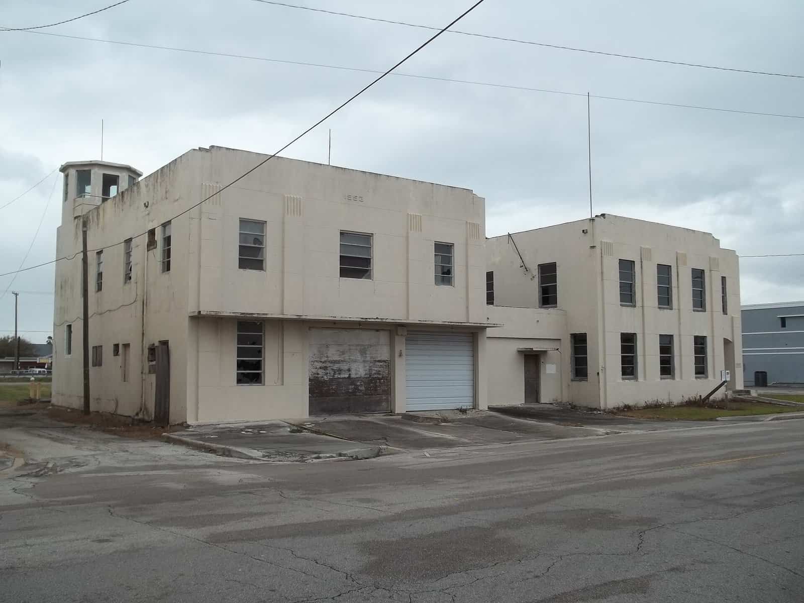 The old two-story city hall and fire station building in Belle Glade, Florida, under an overcast sky