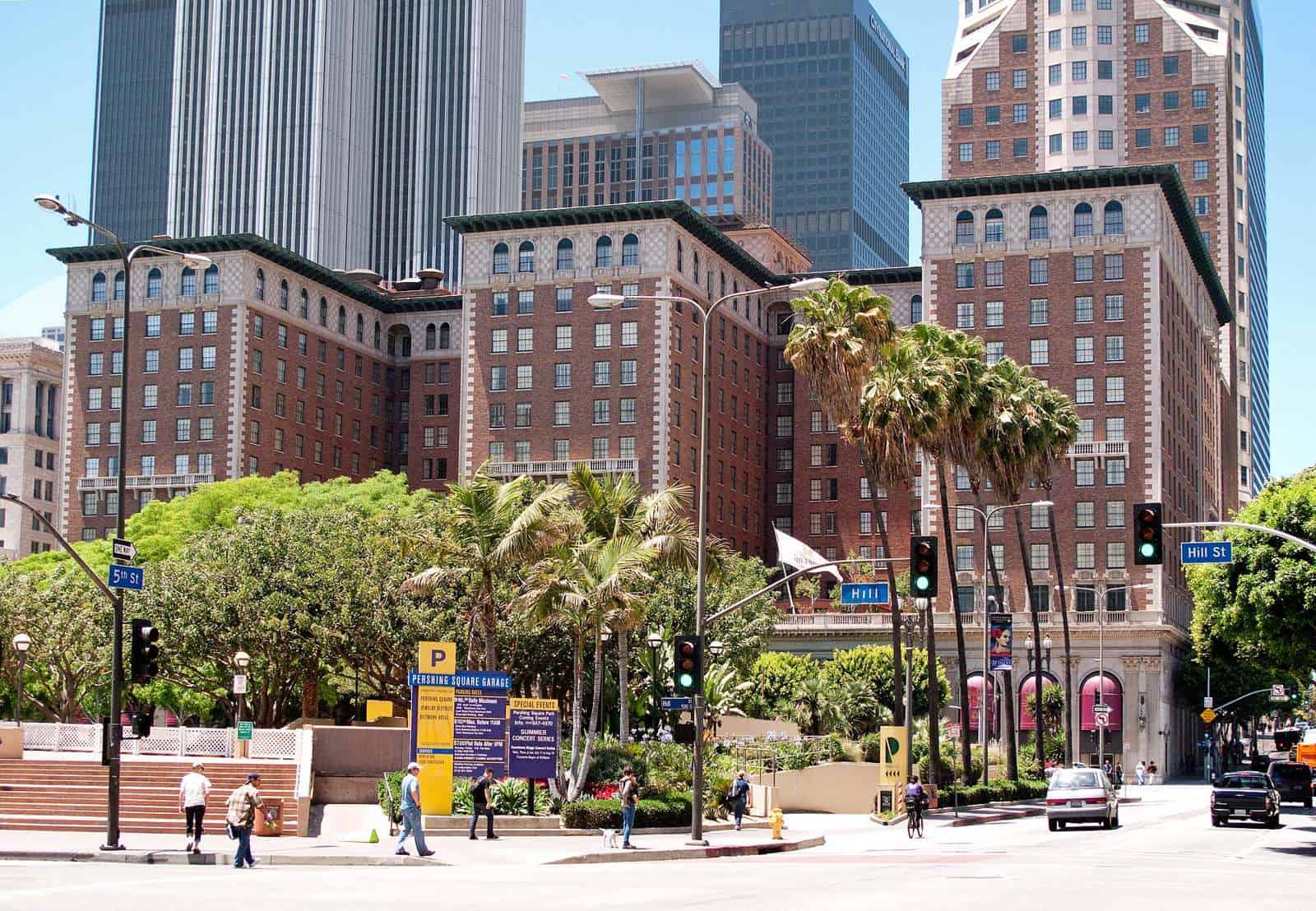 Historic brick building with palm trees and modern skyscrapers in background.