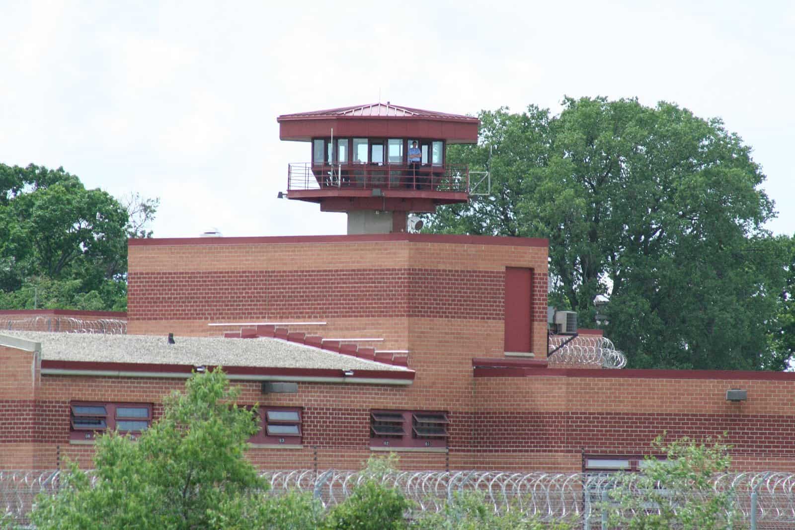 A guard tower above a red-brick building behind razor-wire fencing at Columbia Correctional Institution