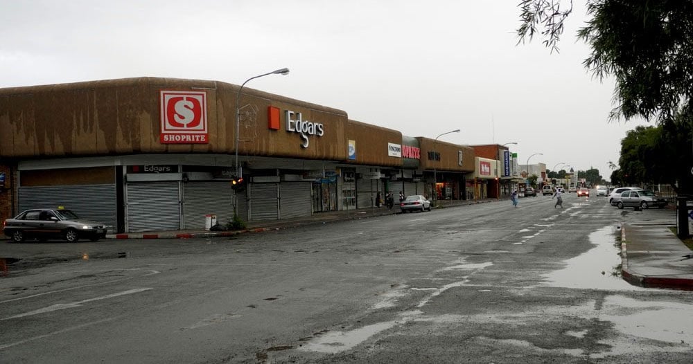 A wet main street lined with shuttered shops in Lichtenburg, South Africa