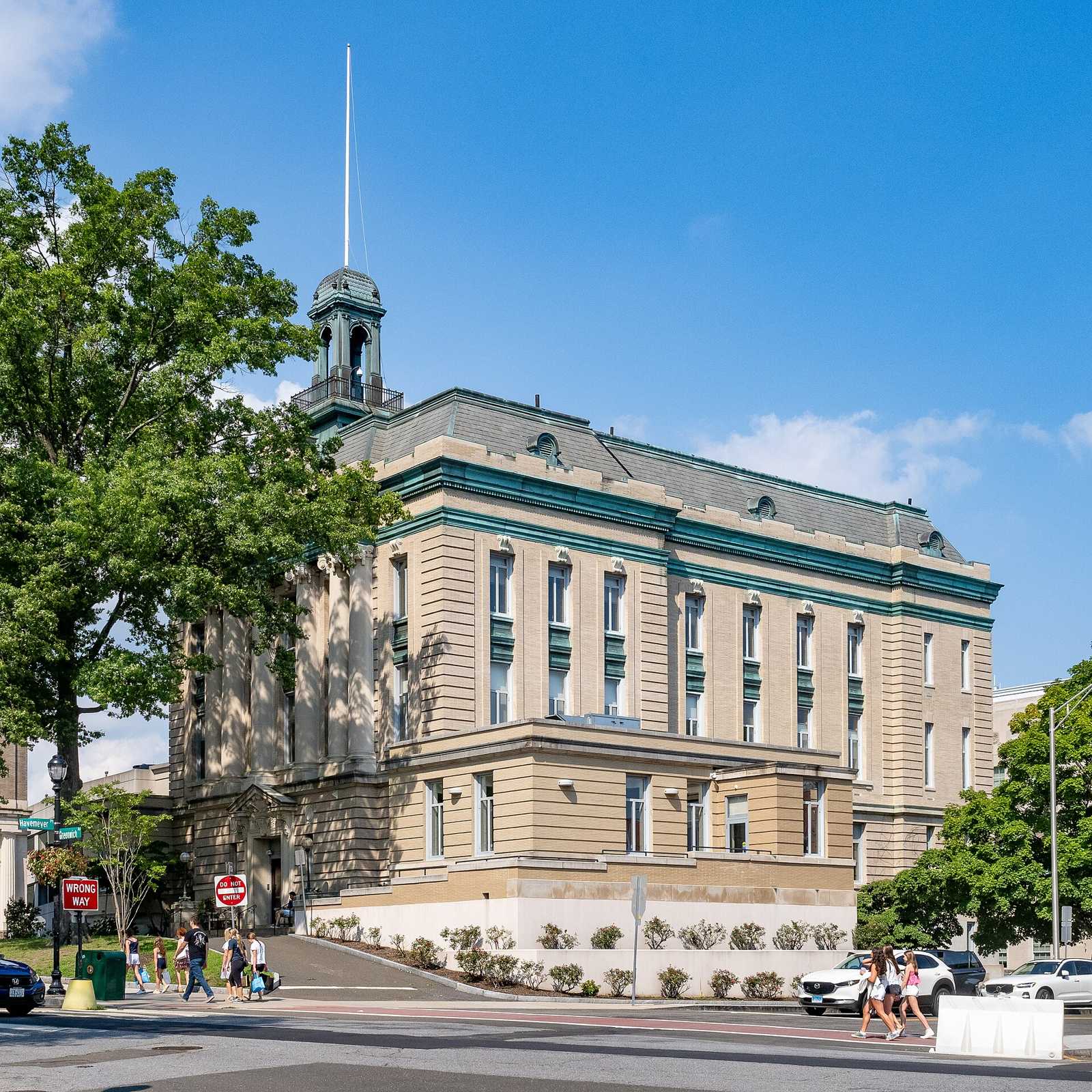 Greenwich Town Hall, a large tan building with a cupola, seen from the street on a sunny day