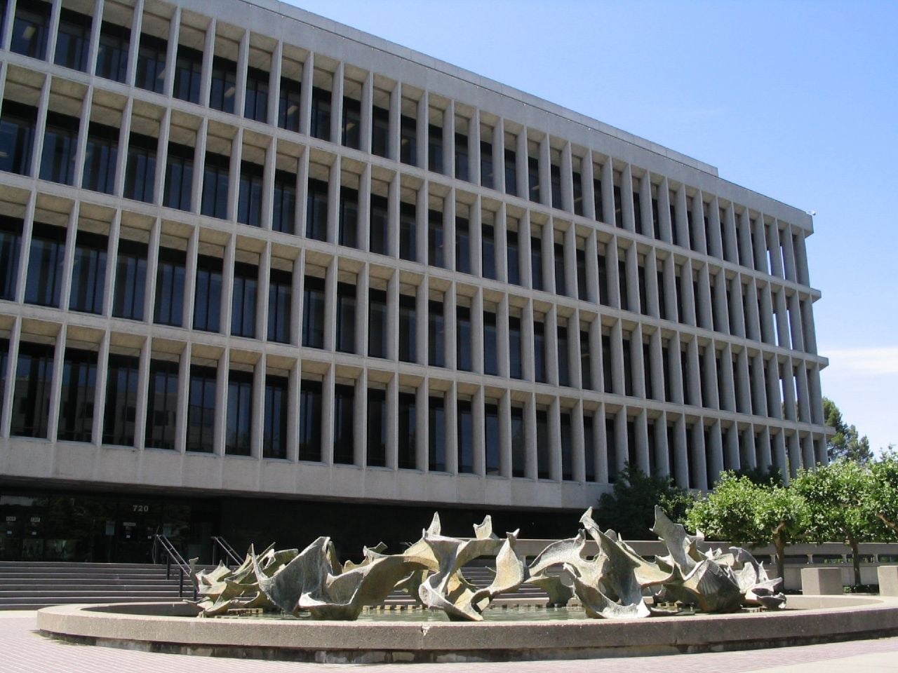 The Gordon D. Schaber Sacramento County Courthouse, a long multistory modernist building with horizontal bands of windows, behind a plaza and trees.