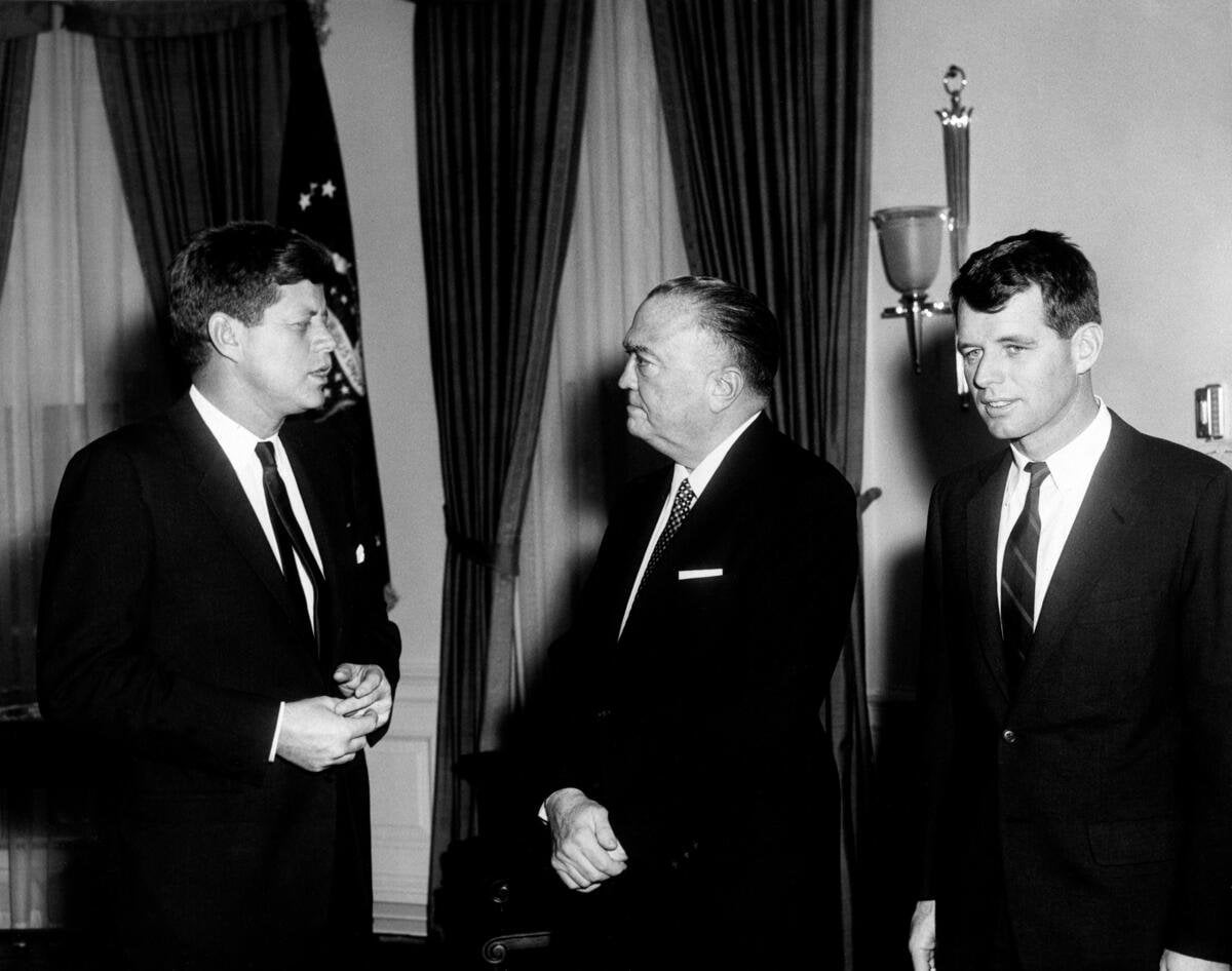 President John F. Kennedy standing in the Oval Office with J. Edgar Hoover and Attorney General Robert F. Kennedy