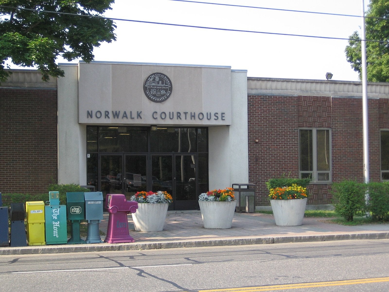 The single story brick and stone Norwalk Courthouse on Belden Avenue, with flower planters along the sidewalk
