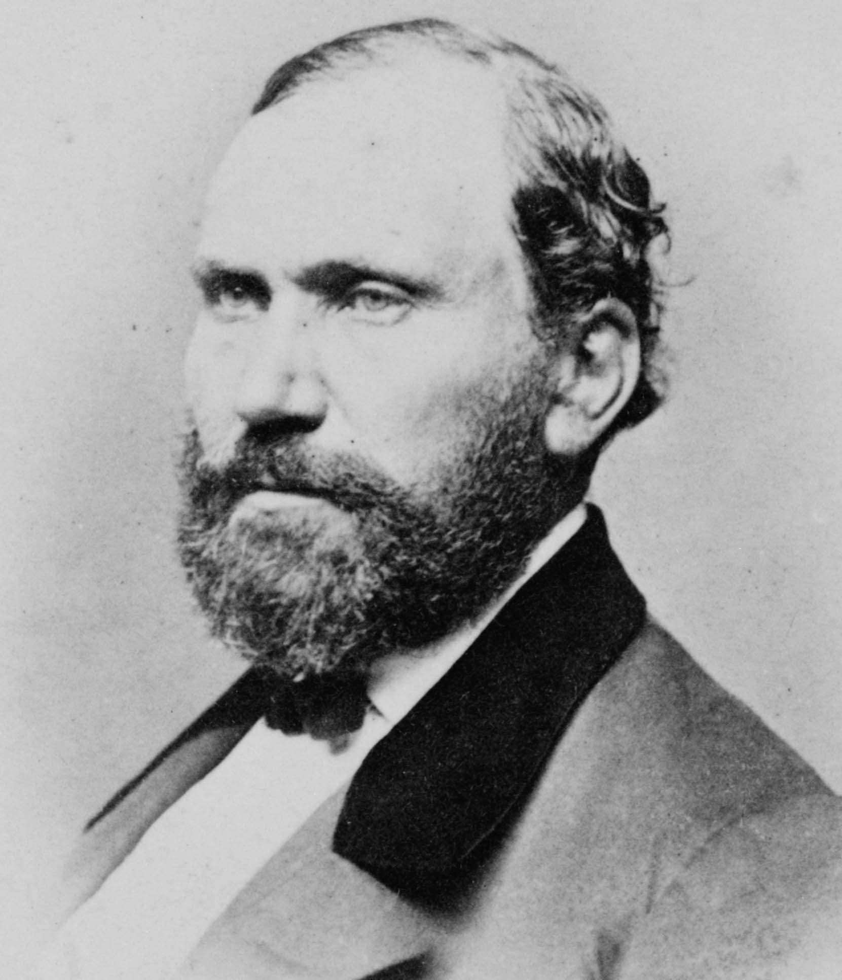 Studio portrait of a bearded man with a high forehead, wearing a dark coat and waistcoat, seated and looking slightly to one side