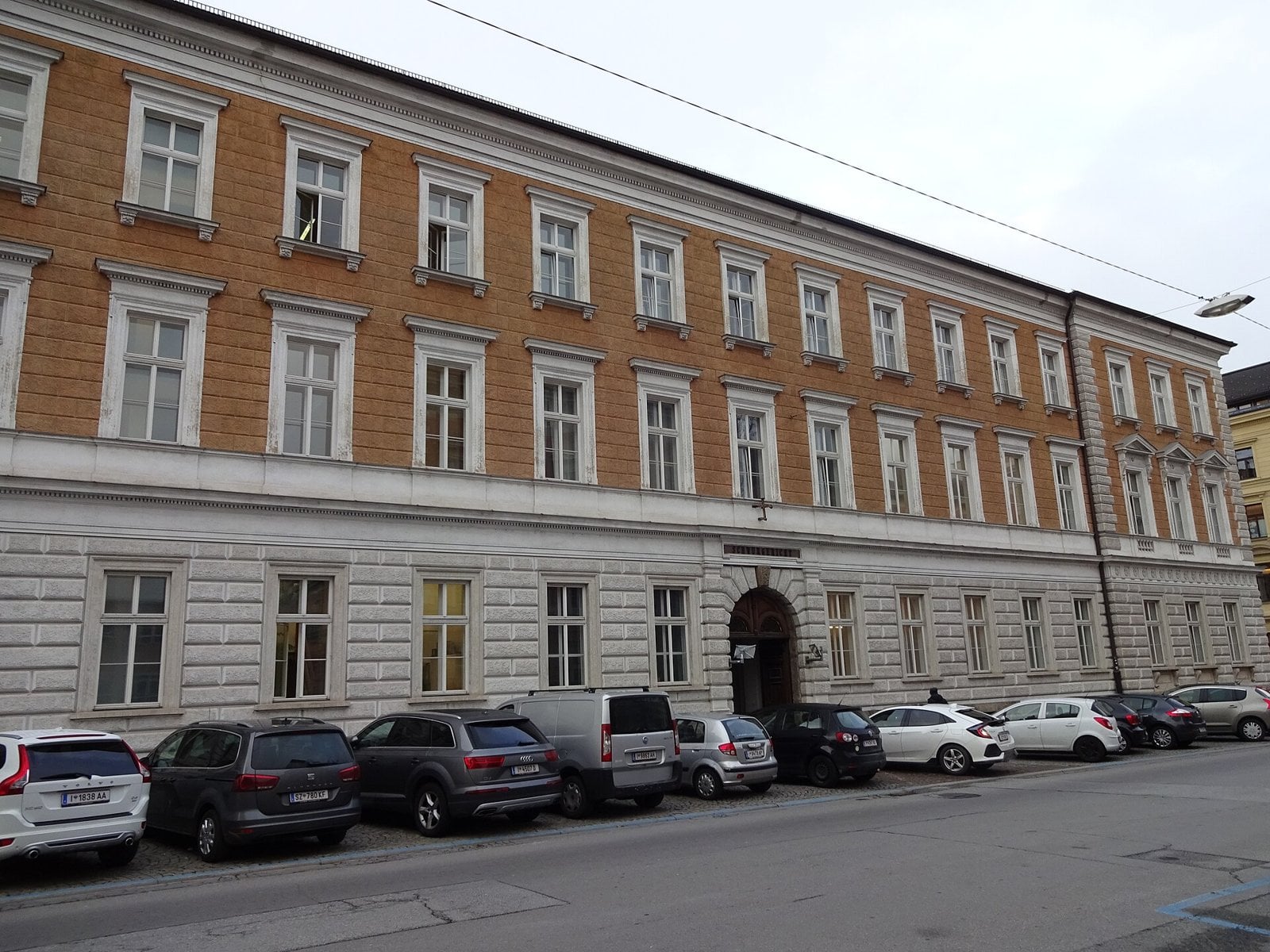 Long facade of the Innsbruck Regional Court with cars parked outside